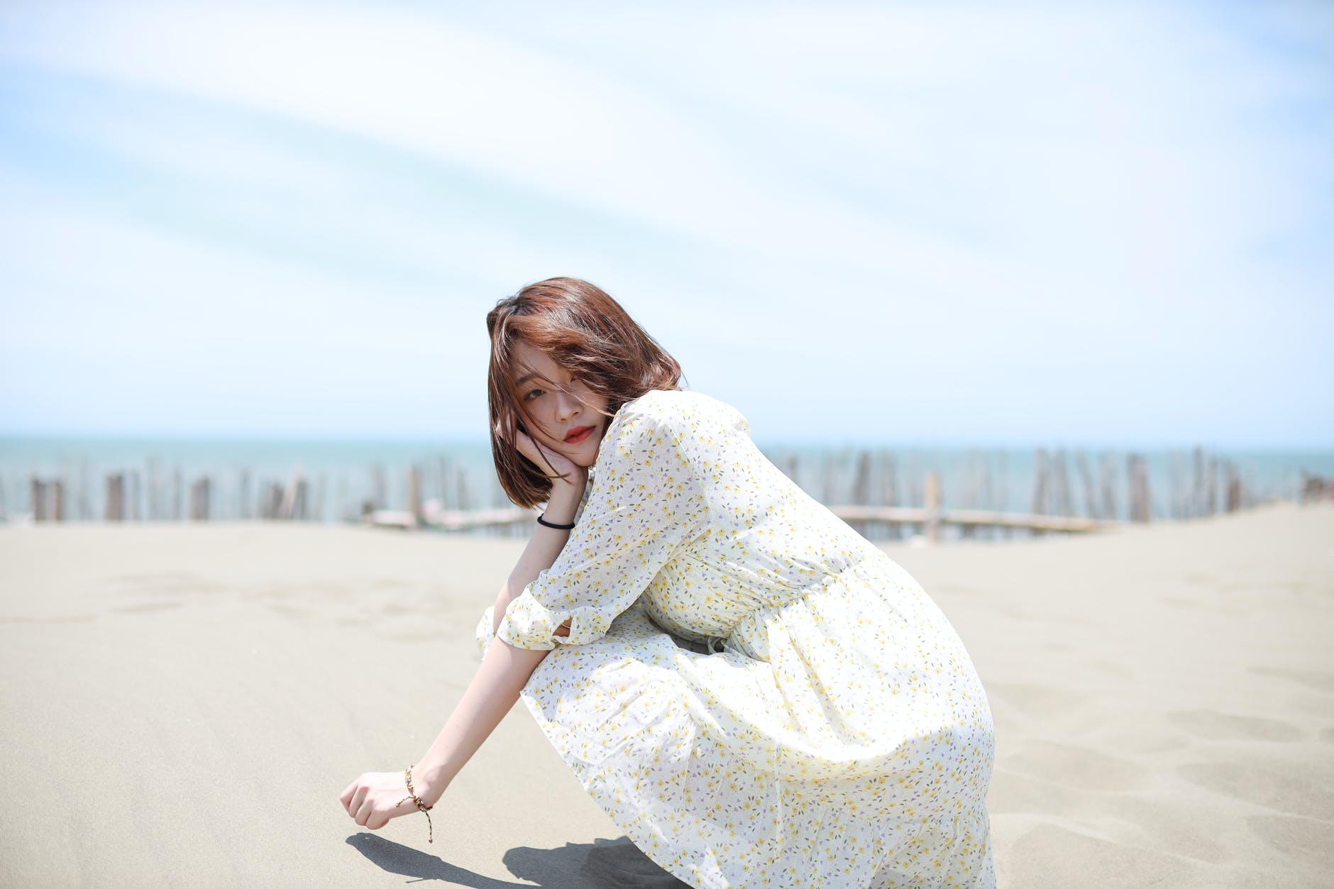 woman in white knit sweater sitting on sand